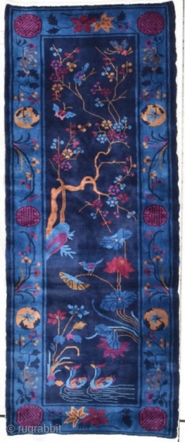 This circa 1900 antique Peking Chinese handmade Oriental rug measures 2’8” X 6’7”. It has a navy blue ground containing two swimming ducks on a water feature out of which are growing  ...