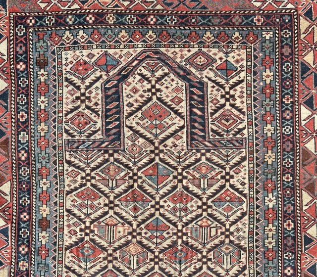 Shirvan prayer rug
This East Caucasian prayer rug shows a characteristic diamond lattice design of dark blue serrated leaves enclosing flowering shrubs in its white field containing the bridge-shaped prayer arch at the  ...