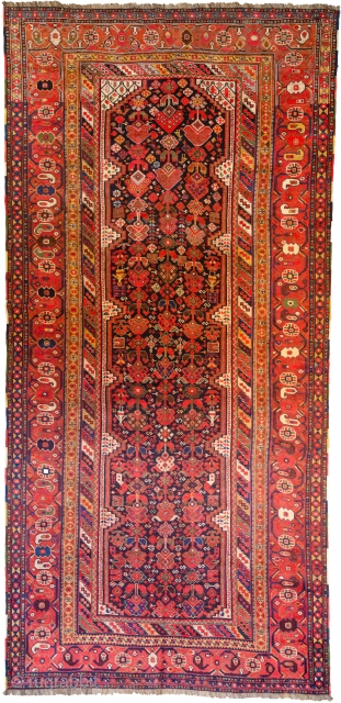 A beautifully drawn antique Khamseh long carpet from the tribes of South Iran. The blue ground has many interesting characters. It is scattered with stylised bushes, flower heads, women and chicken amongst  ...