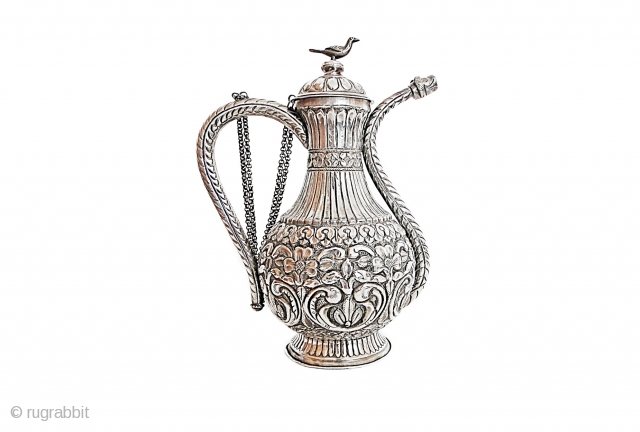 AN OTTOMAN SILVER EWER 

With squat body rising from short splayed foot to waisted neck with pronounced collar, the double curving spout with original stopper, the separate lid with faceted knop finial  ...