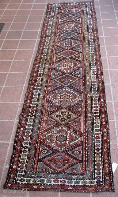 Antique 2' 10" x 13' 10" Kurd.  Lays straight; In low to medium pile condition, with the original end webbings having been sewn underneath. Two very small replied areas on one  ...