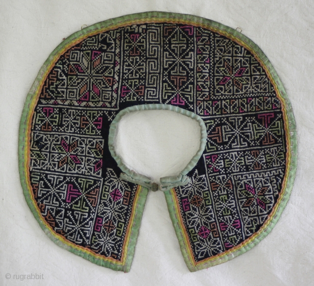 EMT152 This tradition style childs collar of the Chinese Dong Ethnic minority was handmade by the mother or grandmother. The fabric was cut from fragments of handwoven cloth stitched together. The embroidery  ...