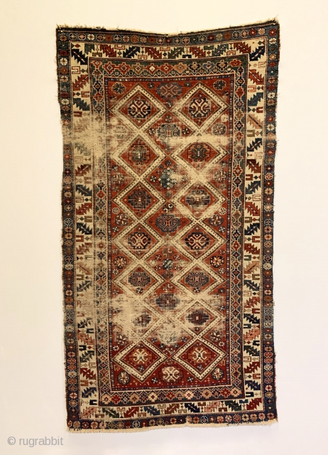 Antique Caucasian Small Rug. Circa Early. Two columns of ivory diamond lattice with alternating rows of gols. Leaf and wine glass border. Remnants of embroidered macrame ends on top. Original condition with  ...