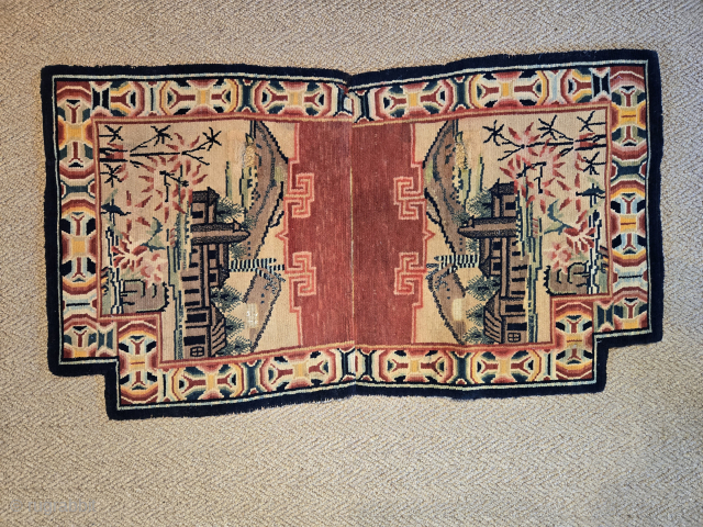 An unusual Tibetan saddle carpet. Rendered in the design of a Bao Tao type design with a Chinese style village or temple scene. The border is sensational. In my estimation this piece ...