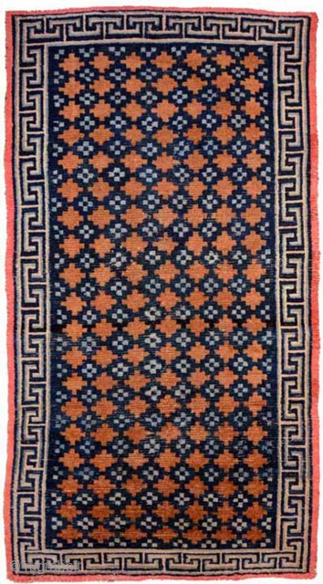 Tibetan khaden with various shades of blue making up the so-called 'gau box', or amulet, design evenly interspaced throughout the brown main field in 'lattice' like pattern. A 'Greek T' main border  ...
