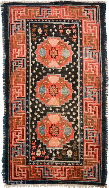 Strikingly vibrant Tibetan khaden with three medallions and the so-called 'frog foot' design scattered throughout the center field. The main border is a well executed interlocking yungdrung (swastika) design with an almost  ...