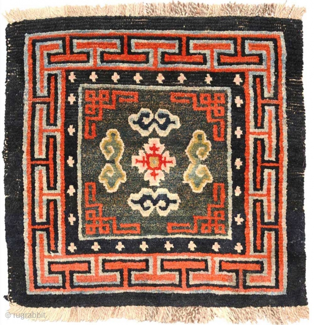 Beautiful richly coloured naturally dyed Tibetan seating carpet. The three dimensional 'Greek T' main border encloses an inner secondary border with crosses that mimic the tie-dyed tigma pattern much beloved by Tibetans,  ...