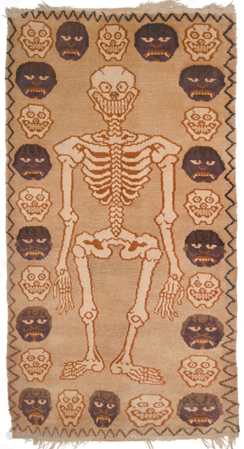 Tibetan tantric rug depicting a grinning skeletal form and alternating grinning skulls and scowling disembodied heads around the perimeter. The colours employed appear to be all natural, both the warp and weft  ...