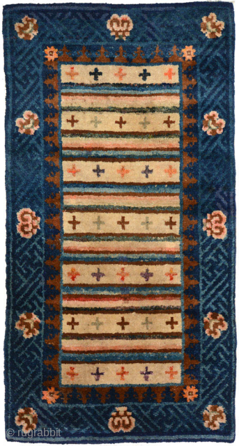 Beautifully coloured small carpet from the Baotou region of China that, given the tigma (cross) design in the striped central field, was probably intended as a seating carpet for the Tibetan market. ...