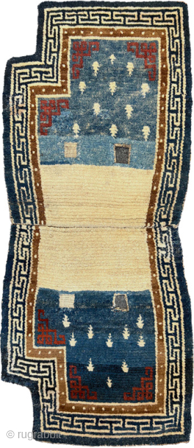 Tibetan under saddle carpet (makden) from the 1800’s / 19th century with the so-called ‘frog-foot’ motif scattered sparingly throughout the main field, an inner border of pearls and an outer border with  ...