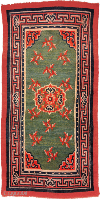 Tibetan khaden with a central mandala-like motif and leaves spread sparingly throughout a subtly abrashed marled-green main field. The main border is the interlocking T design highlighted with flowers at the cardinal  ...