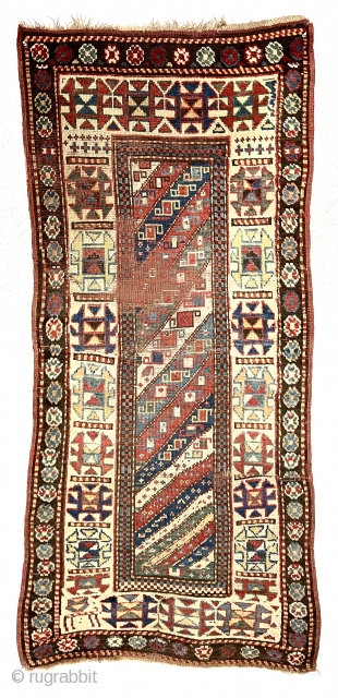 Antique Caucasian Kazak rug with interesting design features and a very unusual narrow size. The weaver altered an otherwise typical diagonal striped field with width and design changes. The extra wide ivory  ...