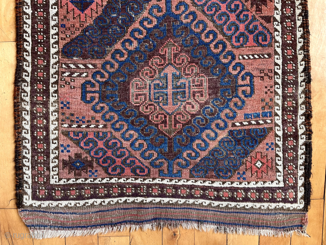 Antique small Baluch rug with some unusual features. A mini runner, rather narrow for its length. In the “mushwani” design family with its latch hooked field. An unusual border  that I  ...