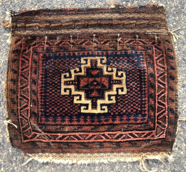 Antique little Baluch bagface with an interesting design feature. The single bold memling gul floats on an unusual checked ground. Overall good even pile. Some brown  oxidation. Creases. Natural colors. Original  ...