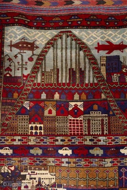 C107. A great example of a naive art “peace” period rug. 1990s. An imagined city that has everything - a big bridge, houses, office buildings aircraft, cars, boats, street lighting. 180x133cm. 5’11”x4’4”.  ...