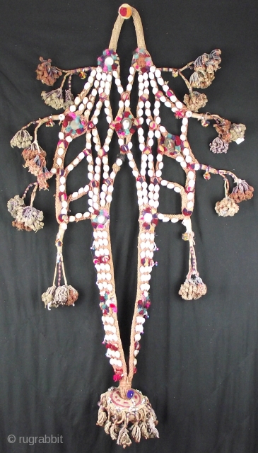 Decorative rope camel trapping, this vintage piece is embellished with shells, mirrors and tassels with a large central fringed rope pom pom.
This would be worn by placing over the head and neck  ...