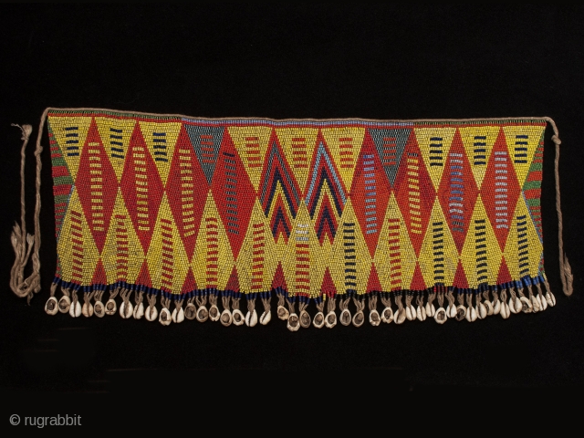 Pikuran (cache-sex), Bana Guili people, Mandara Mountains, Cameroon. Seed beads, cotton string, cowrie shells, 21" (53.3 cm) wide by 9" (22.8 cm) high Mid 20th century. These colorful cache-sex were worn for  ...