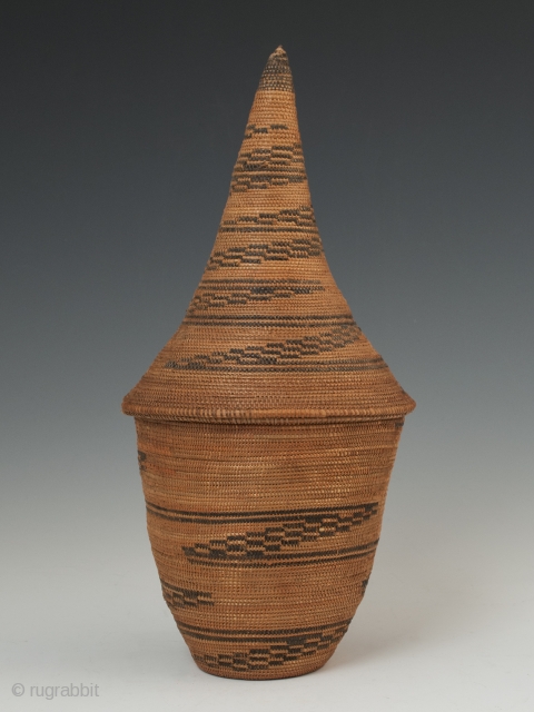 Presentation basket (Igiseke), Tutsi people, Rwanda. Plant fibers, natural dye. 8.75" (22.2 cm) high by 4" (10 cm) wide. Mid 20th century, ex. private collection, New York.

Baskets such as this often contained  ...