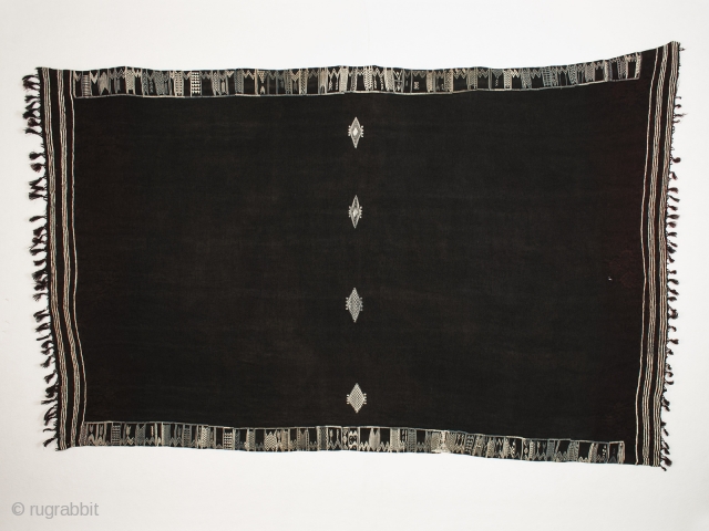 Baknough (woman's head covering), Berber people, Libya. Wool, cotton, indigo, henna, 20th century, 44" to 52" (195 to 132 cm) high by 74" (91.5 cm) long 

This baknough is most likely from  ...