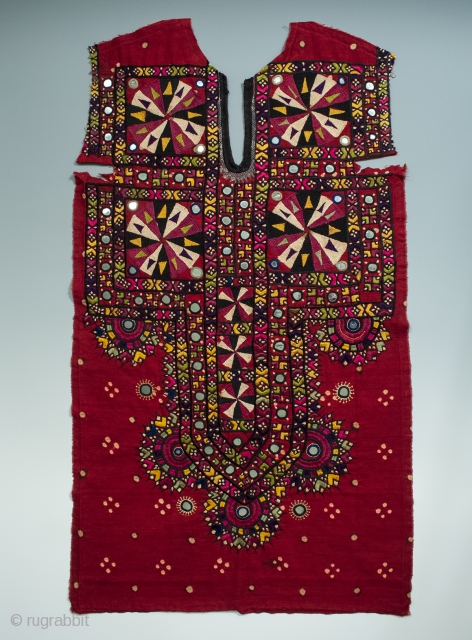 An embroidered shirt front from the Sindh region of Pakistan. Deep red cotton with some tie-dyed dots covered with silk thread embroidery and mirrored disks scattered throughout. In great condition with all  ...