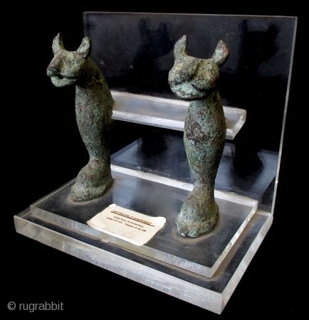 Antique Pair of Egyptian Bronze Cats

Egyptian bronze pair of cat figures with overall wear and green patina. Pierced holds through the mouths, heads, necks, and bases suggest they may have once been  ...