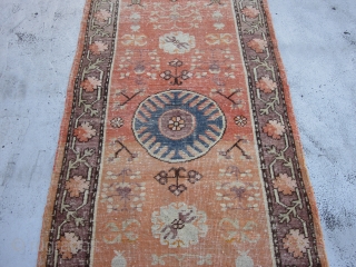 Small Khotan Runner circa 1920's , 6.8 x 2.5
A round,mid blue medallion centers a salmon field ornamented with fruits,stylized flowers,rosettes and leafy quatrefoils.The mauve-brown border of rosettes and stiff vines is also  ...