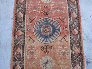 Small Khotan Runner circa 1920's , 6.8 x 2.5
A round,mid blue medallion centers a salmon field ornamented with fruits,stylized flowers,rosettes and leafy quatrefoils.The mauve-brown border of rosettes and stiff vines is also  ...