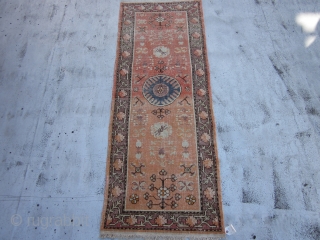 Small Khotan Runner circa 1920's , 6.8 x 2.5
A round,mid blue medallion centers a salmon field ornamented with fruits,stylized flowers,rosettes and leafy quatrefoils.The mauve-brown border of rosettes and stiff vines is also  ...