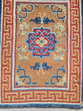 Tibetan small rug or saddle top with a camel ground, abrashed blue vine-scroll and a red central quatrefoil medallion. Nice auspicious bat-like butterflies          