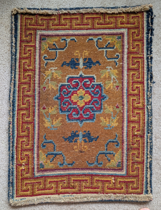 Tibetan small rug or saddle top with a camel ground, abrashed blue vine-scroll and a red central quatrefoil medallion. Nice auspicious bat-like butterflies          