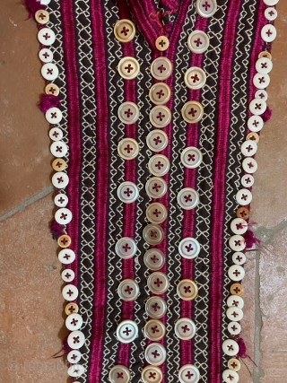 Tajik young girl's cap with the traditional "tail" to hide the plait. The cap is heavily embroidered in stripes of cherry red, alternating with white geometric bands, which show the dark ground.  ...