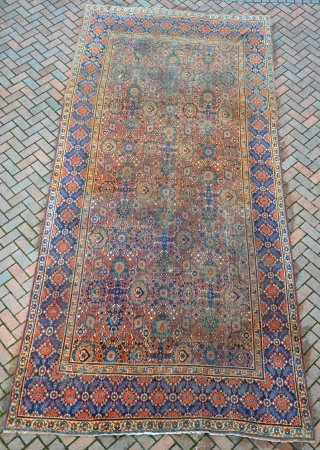 An antique Khorrasan carpet, some wear but complete, still retaining its original sides and fine blue kilim ends. 462x220cm. Early 19th century           
