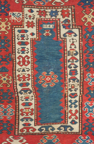 Kazak prayer rug, dated to about 1876. The date is inscribed at the top of the mihrab. 
Note the abstracted beast to the left of the top of the mihrab. Also note  ...