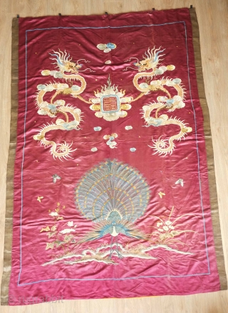 Qing Chinese hanging, late 19th century. The fabulous peacock tands with opened tail in exceptional embroidered detail with two dragons facing each other above.  The dragons are four clawed and are  ...