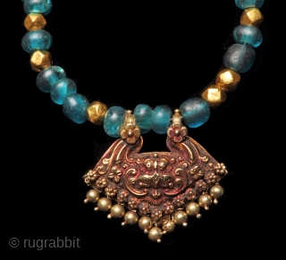 Indian gold KirtiMuka pendant with blue glass beads from the Majapahit period 15th c. and gold beads.                