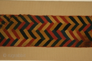 Belt fragment, Paracas Ocucaje culture, Peru, plaited camelid wool, circa 300-100 BC, actual piece is 4 x 30 inches, mounted dimensions are 7 x 33 inches.       
