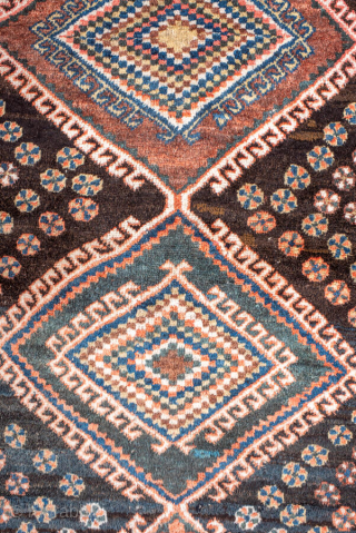 Antique Persian Kurdish Rug, circa 1910. Featuring bold diamond medallions on a dark field with scattered rosettes and tribal motifs, framed by a cream geometric border. Strong village character with lively, graphic ...