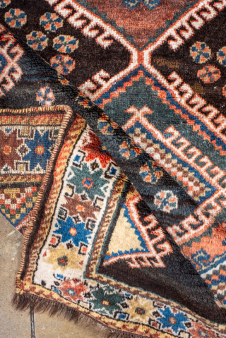 Antique Persian Kurdish Rug, circa 1910. Featuring bold diamond medallions on a dark field with scattered rosettes and tribal motifs, framed by a cream geometric border. Strong village character with lively, graphic ...