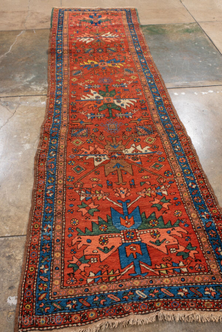 Antique Persian Heriz Runner, circa 1910. Featuring bold geometric medallions on a vibrant red field with blue and ivory accents, framed by a classic Heriz border. Strong Northwest Persian village design with  ...