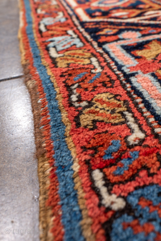 Antique Persian Heriz Rug, circa 1900. Featuring a striking geometric medallion on a vivid rust-red field with deep navy and ivory accents, framed by a bold angular border characteristic of Northwest Persian ...