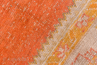 This antique Oushak rug showcases the beauty of Anatolian weaving with its striking open field in warm terracotta red, framed by soft blush, ivory, and golden tones. The spacious design and gentle  ...