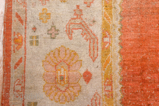This antique Oushak rug showcases the beauty of Anatolian weaving with its striking open field in warm terracotta red, framed by soft blush, ivory, and golden tones. The spacious design and gentle  ...