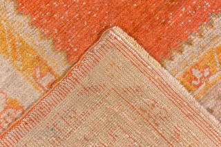 This antique Oushak rug showcases the beauty of Anatolian weaving with its striking open field in warm terracotta red, framed by soft blush, ivory, and golden tones. The spacious design and gentle  ...