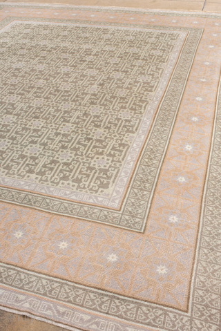 This elegant antique Oushak rug showcases a beautifully detailed allover lattice design in soft sage green and ivory, framed by a wide border in warm peach and golden tones. Its geometric patterning  ...