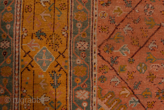 This antique Turkish Oushak rug, woven circa 1900, showcases a beautifully understated lattice and medallion design on a rich rust field framed by a wide gold border with delicate floral detailing. The  ...