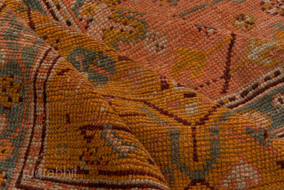 This antique Turkish Oushak rug, woven circa 1900, showcases a beautifully understated lattice and medallion design on a rich rust field framed by a wide gold border with delicate floral detailing. The  ...