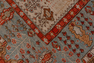 This antique Oushak rug, woven circa 1900, features a captivating Tree of Life design with stylized floral and botanical motifs cascading across an ivory field. The delicate, painterly pattern is framed by  ...