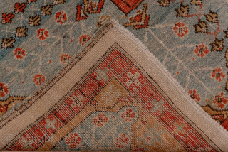 This antique Oushak rug, woven circa 1900, features a captivating Tree of Life design with stylized floral and botanical motifs cascading across an ivory field. The delicate, painterly pattern is framed by  ...