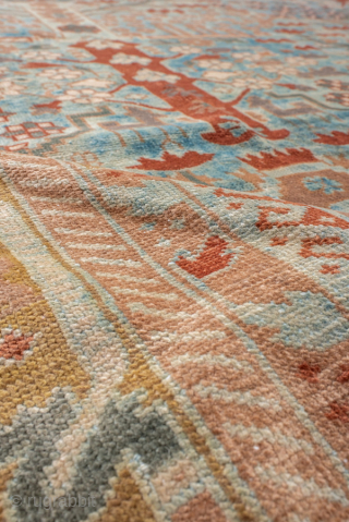 This antique Sivas rug, woven circa 1920, showcases a striking botanical garden design with stylized floral motifs and tree forms arranged in a symmetrical lattice pattern. The soft blue field is accented  ...