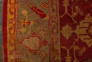 This antique Turkish Oushak rug, woven circa 1900, features a striking deep red field adorned with soft gold and muted blue floral motifs. The wide, decorative border frames the design beautifully, showcasing  ...